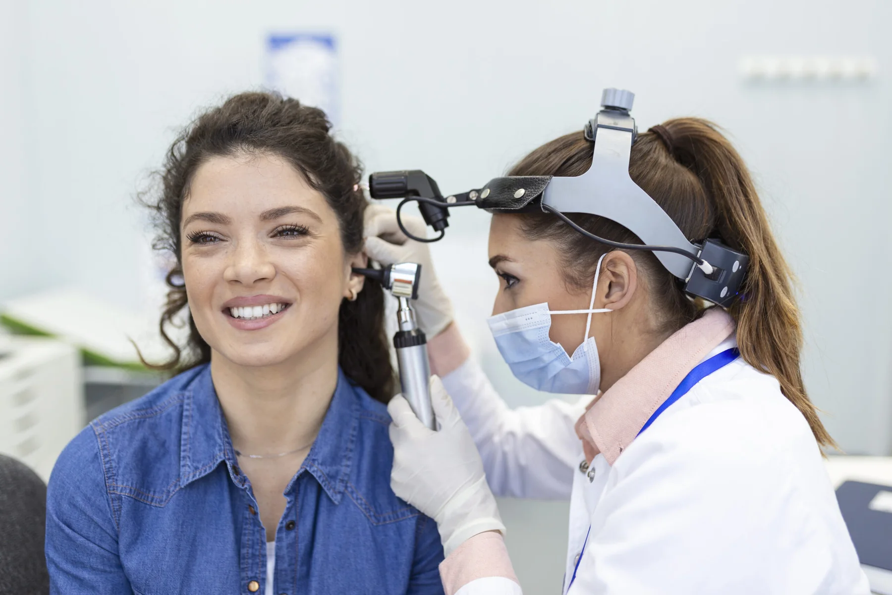 Clinician examining a smiling patient's ear
