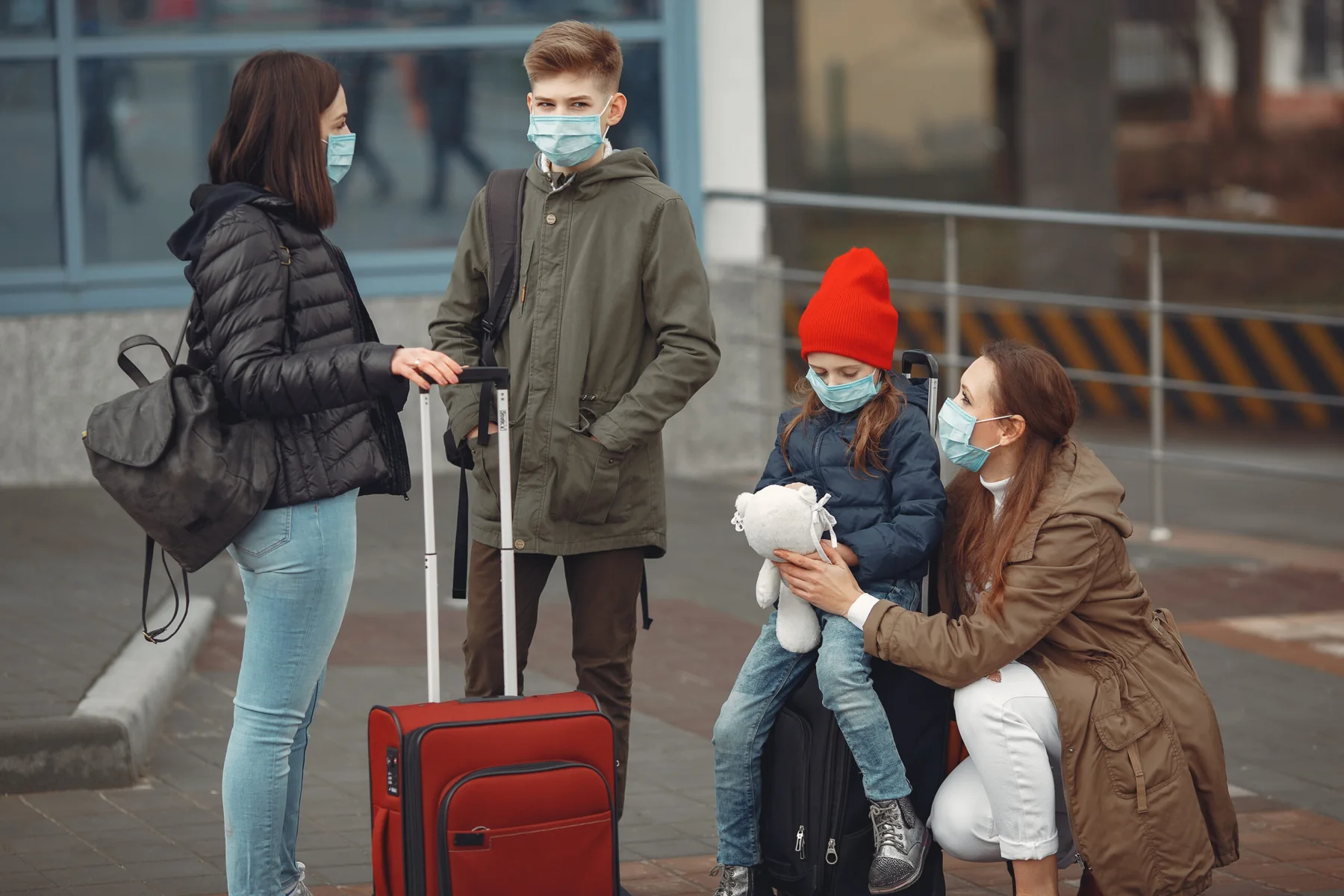 Family wearing face masks at an airport with their luggage